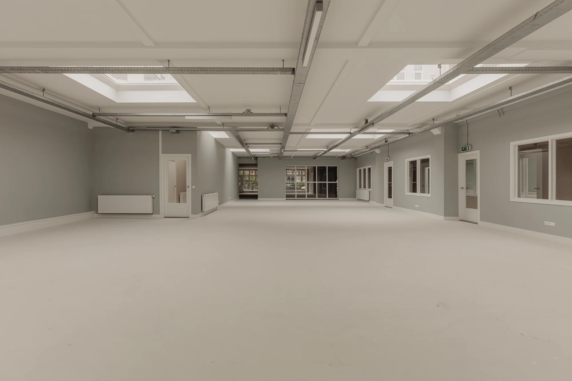 Lichte, lege kantoorruimte aan de Henri Polaklaan met grote ramen en daklichten.